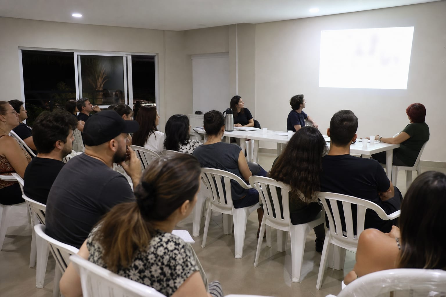 Moradores reunidos em assembleia no salão de festas do condomínio à noite