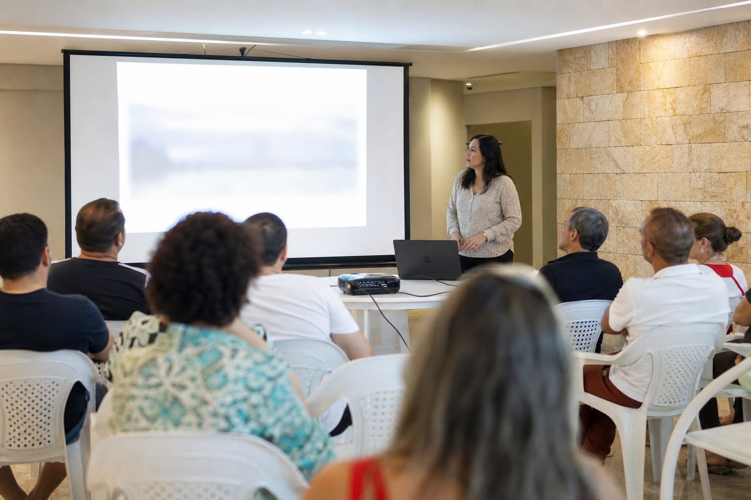 Síndica apresenta resultado ao lado da tela de projeção durante assembleia